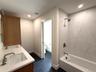 Bathroom featuring double sink vanity and bathtub with shower