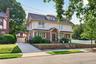 Two-story residence featuring a brick and stucco exterior, prominent front porch with columns, a multi-car driveway, and a detached two-car garage