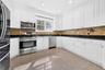 Kitchen featuring extensive white cabinetry, stainless steel appliances, dark countertops, a tiled backsplash, and recessed lighting