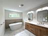 Primary Bathroom featuring a freestanding soaking tub and dual vanity with wood cabinetry