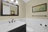 The updated hall half bathroom on the first floor features wainscotting, crown molding and a Corian vanity with a beautiful tri-fixture light.