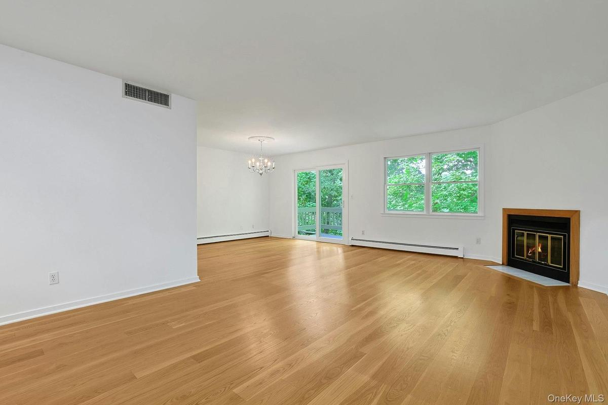 The expansive living room has bright, wood floors that shine from the natural light that flows in from the large windows and sliding doors to the deck