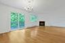 Centered under an elegant chandelier with a rosette, the dining room has sliding doors out to the rear deck.
