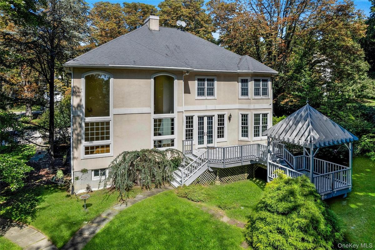 Stucco exterior with multi-pane windows, elevated deck, and a gazebo