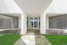 Oversized columns and elegant glass double doors frame a spectacular modern entry framed by curved glass-block privacy walls.