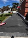 Brick exterior with a red fabric awning, asphalt driveway, and a white picket fence