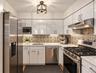 Contemporary kitchen featuring stainless steel appliances, white cabinetry, patterned tile backsplash, and light countertops