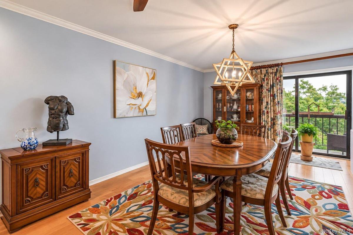Light wood-finish flooring with crown molding and a prominent chandelier