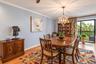 Light wood-finish flooring with crown molding and a prominent chandelier
