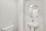 Pedestal sink, wall-mounted oval mirror, and white toilet