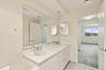 Dual vanity with integrated sinks and chrome fixtures, framed by a large wall mirror
