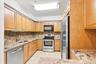 Kitchen featuring wood cabinetry, stainless steel appliances, tiled backsplash, and stone countertops