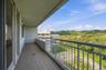 Balcony featuring tile flooring, a metal railing, and a verdant landscape backdrop