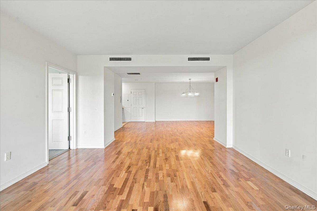 Hardwood flooring throughout, white painted walls, recessed lighting, and a contemporary pendant light fixture