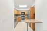 Kitchen featuring wood cabinetry, stainless steel appliances, a tiled backsplash, and a breakfast bar with a stone-finish countertop