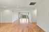 Wood-finish flooring throughout, recessed ceiling lighting, light-colored walls, and a large sliding glass door opening to an exterior balcony