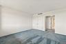 White walls, light blue carpeting, and dual panel doors with dark hardware