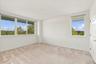 Expansive room featuring multiple windows, neutral carpet flooring, and a flat white ceiling