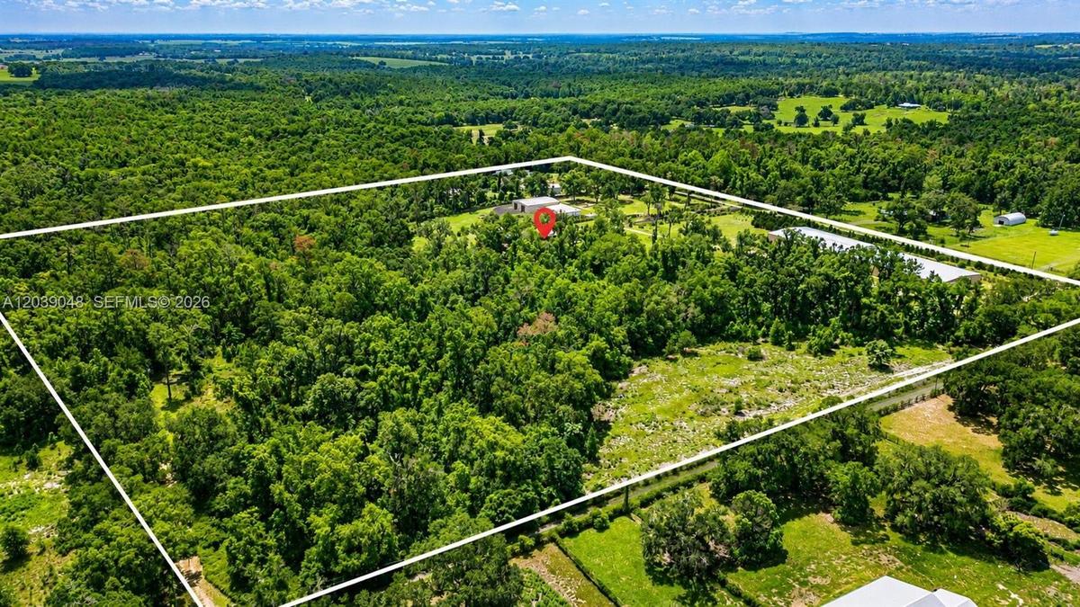Stunning aerial perspective showcasing over 24 acres of usable land, offering privacy, expansion potential, and multiple structures including the resi