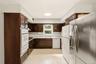 Dark wood-finish cabinetry, white countertop, built-in double oven, and a circular ceiling light fixture
