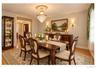 Hardwood flooring, crystal chandelier, decorative wall paneling, built-in display cabinet, and wall sconces
