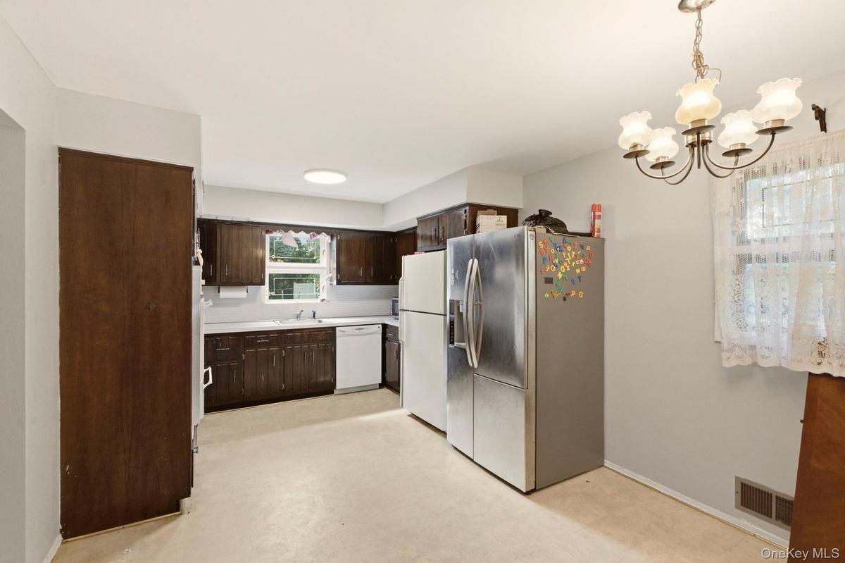 Kitchen featuring wood-finish cabinetry, light-toned countertops, and a ceiling-mounted light fixture
