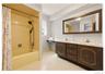 Dual-sink vanity with a marbelized countertop, wood-finish cabinetry, and a large framed mirror