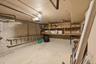 Garage space featuring concrete walls, built-in wooden shelving, and an overhead garage door mechanism