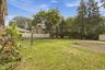 Expansive lawn area, mature trees, white picket fencing, and paved surface