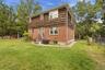 Brick and wood-shingle exterior with multiple windows and a grassy yard