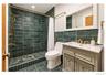 Bathroom featuring green tiled walls, coordinated tile flooring, a shower with a built-in bench, a vanity with a white countertop, and brass-finish fi