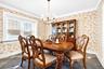 Dining space featuring wallpapered walls, a chandelier, and crown molding