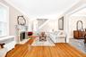 Living area with radiator heating unit, crown molding, wallpapered walls, a glass covered fireplace, and hardwood / wood-style floors