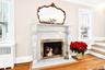 Detailed view of a premium fireplace, radiator, wood finished floors, and ornamental molding