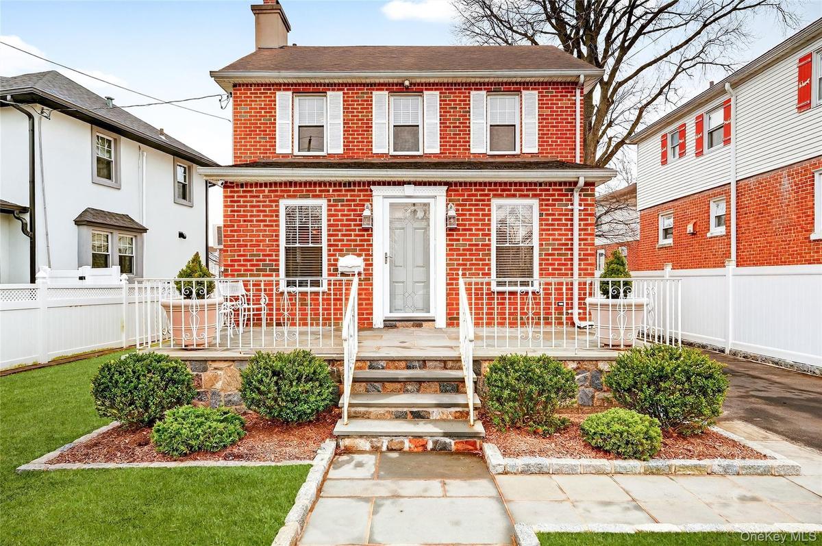View of front of home with brick siding and a chimney