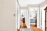 Hallway with light wood-type flooring and ornamental molding