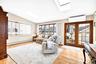 Living area with a skylight, a baseboard radiator, lofted ceiling, a wall mounted AC, and plenty of natural light