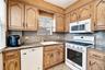 Kitchen featuring white appliances, tasteful backsplash, light tile patterned floors, and light stone counters