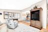 Living room featuring vaulted ceiling, a chandelier, light wood-type flooring, a baseboard heating unit, and a baseboard radiator