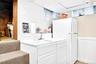 Kitchen with freestanding refrigerator, a wainscoted wall, a drop ceiling, white cabinets, and light countertops