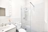 Bathroom with walk in shower, vanity, decorative backsplash, and tile walls