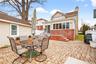 Back of property featuring outdoor dining space, a patio, a chimney, brick siding, and roof with shingles