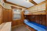 Wood paneling walls, wood-finish bunk bed, wood-frame window, exposed wood beams, and carpeted flooring