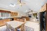 Kitchen featuring light wood cabinetry, black countertops, tile flooring, and a skylight