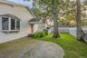 Stone patio with a curved edge, shingle siding, a bay window, and a covered entry