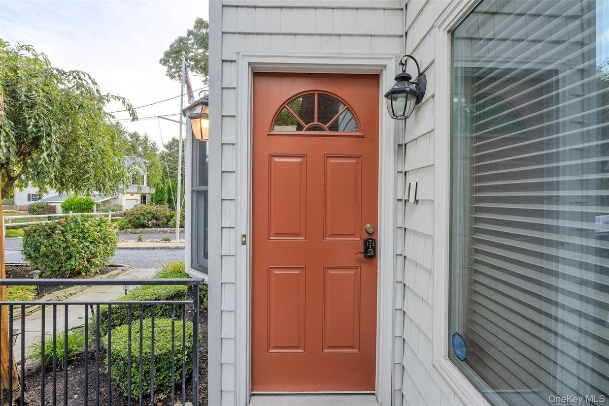Warm entry door with an arched transom, detailed paneling, and an integrated smart lock