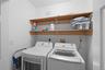 Laundry area featuring dual built-in shelves and white walls