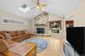 Vaulted ceiling with skylight, stone-clad fireplace, wood-finish flooring, and a ceiling fan