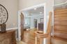 Entryway featuring a wooden staircase with a banister, wood flooring, and a doorway leading into a room with wood flooring and a ceiling fan