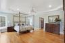 This expansive room features hardwood floors, light blue walls, and a white tray ceiling with recessed lighting